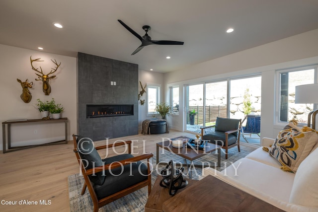 living room featuring hardwood / wood-style flooring, ceiling fan, and a fireplace