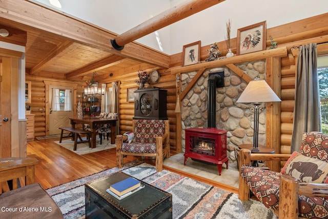 living room with wood ceiling, log walls, a wood stove, light hardwood / wood-style flooring, and beam ceiling