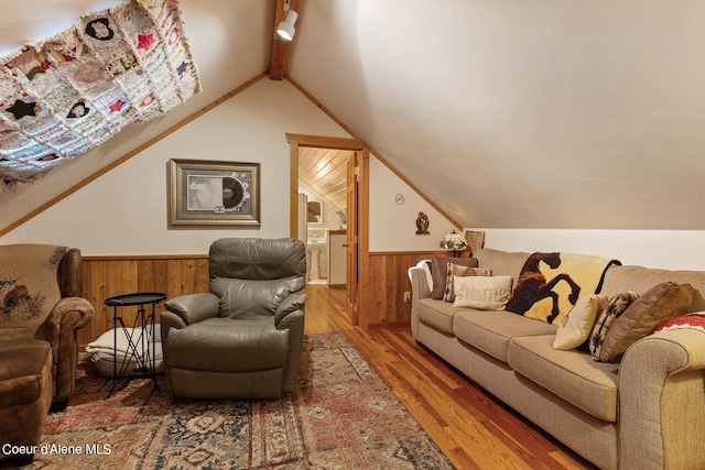 living room with hardwood / wood-style floors, vaulted ceiling with beams, and wooden walls