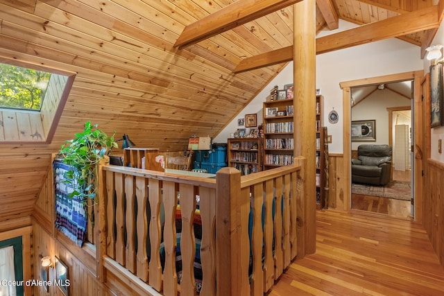 interior space featuring wood walls, light hardwood / wood-style floors, wooden ceiling, and lofted ceiling with skylight