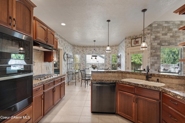 kitchen with decorative light fixtures, a textured ceiling, stainless steel appliances, and sink