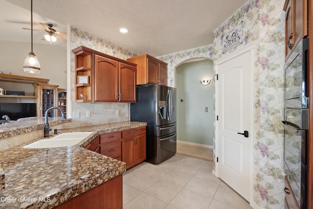 kitchen featuring hanging light fixtures, light tile patterned floors, black appliances, ceiling fan, and sink