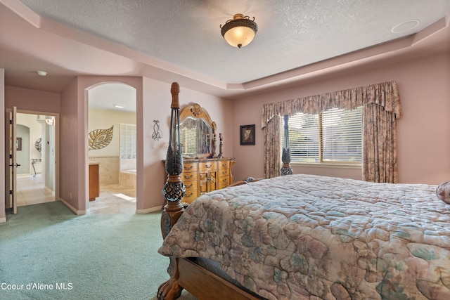 carpeted bedroom with ensuite bath and a textured ceiling