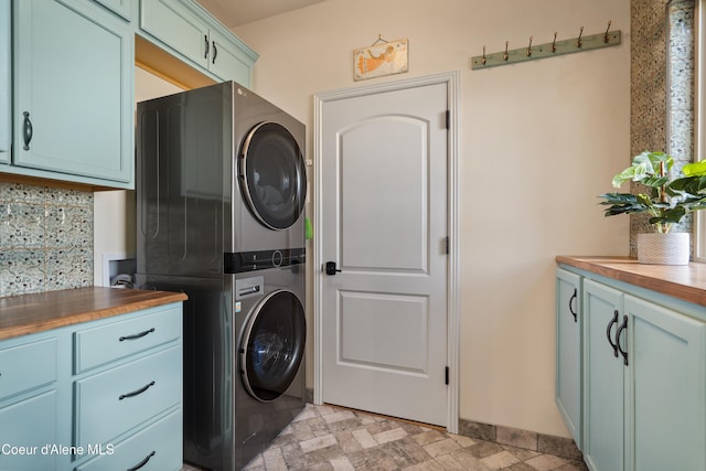 laundry room with cabinets and stacked washer / drying machine