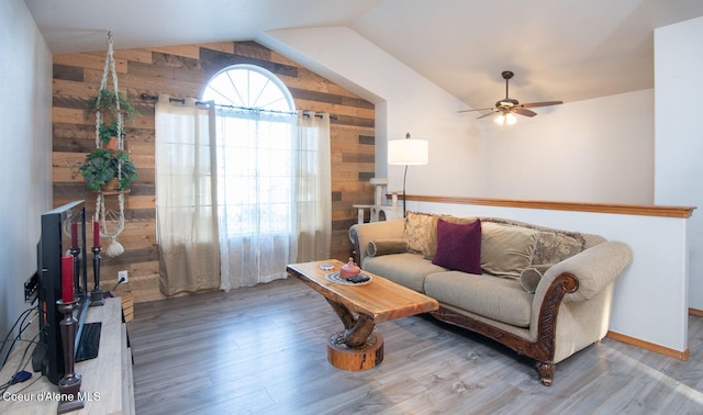 living room featuring ceiling fan, wooden walls, hardwood / wood-style floors, and lofted ceiling