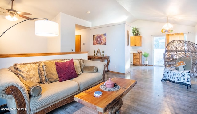 living room with ceiling fan with notable chandelier, lofted ceiling, and dark hardwood / wood-style flooring