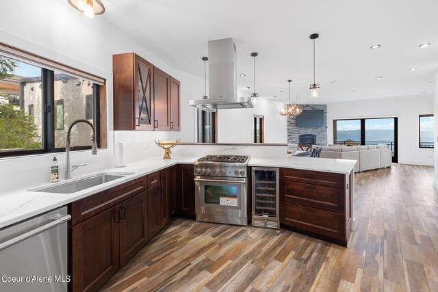 kitchen with wine cooler, sink, dark wood-type flooring, appliances with stainless steel finishes, and a fireplace