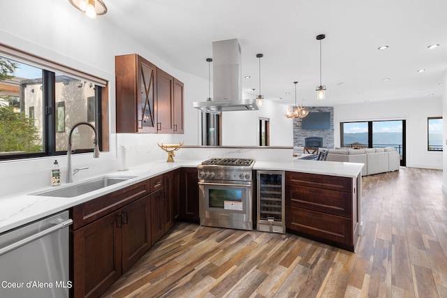 kitchen with a sink, appliances with stainless steel finishes, wood finished floors, island exhaust hood, and beverage cooler