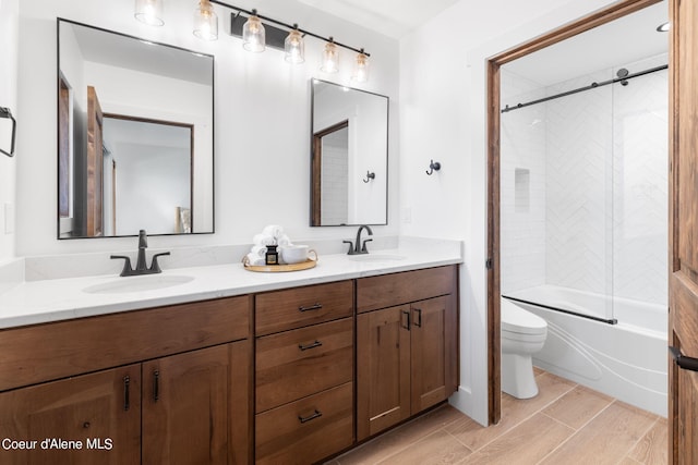 bathroom with wood finish floors, toilet, a sink, washtub / shower combination, and double vanity