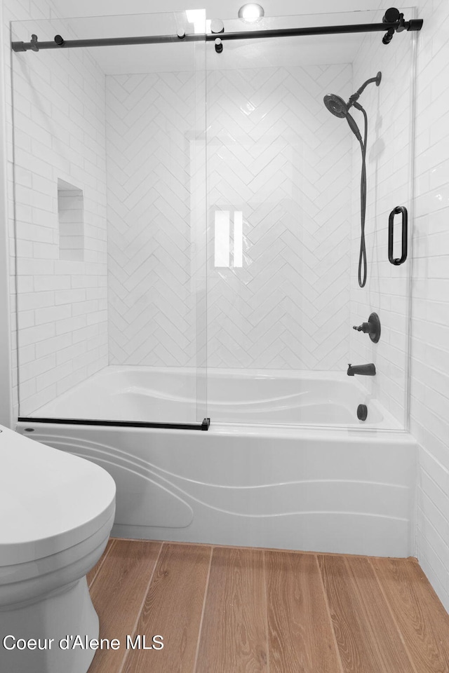 bathroom with toilet, enclosed tub / shower combo, and wood finished floors