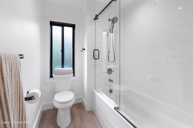 full bathroom with enclosed tub / shower combo, baseboards, toilet, and wood finished floors