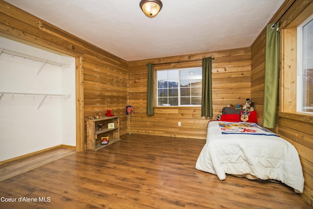 bedroom featuring wooden walls, baseboards, and wood finished floors