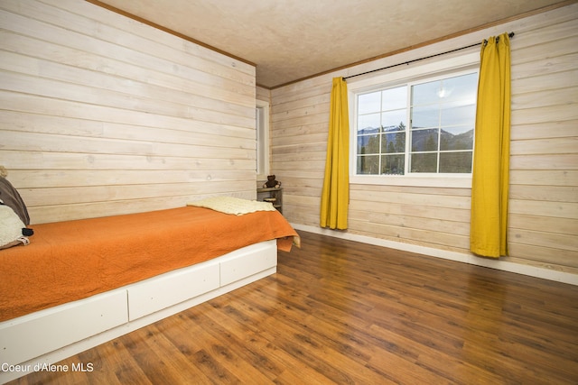 bedroom featuring baseboards, wood walls, and wood finished floors