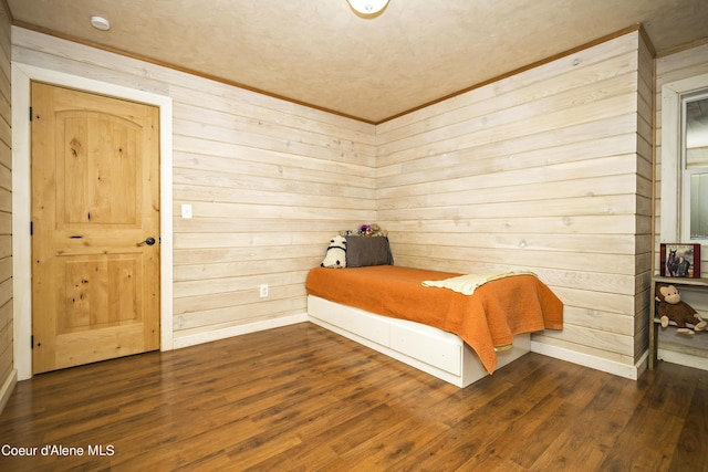 bedroom with baseboards, ornamental molding, wood walls, and wood finished floors