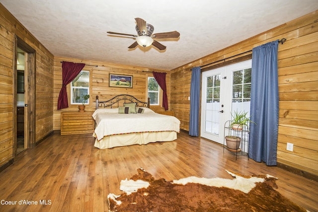 bedroom with wood walls, hardwood / wood-style flooring, and access to exterior