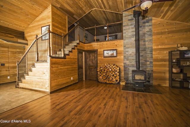 unfurnished living room with a wood stove, wood ceiling, and wooden walls