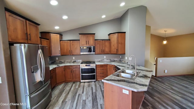 kitchen featuring kitchen peninsula, stainless steel appliances, lofted ceiling, decorative light fixtures, and sink