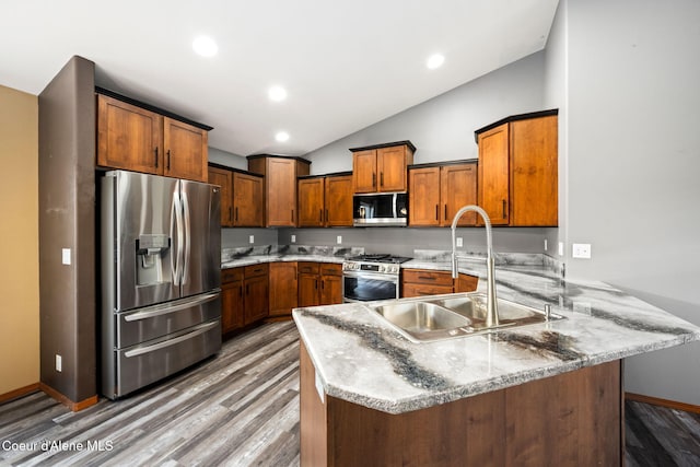 kitchen featuring wood-type flooring, sink, vaulted ceiling, kitchen peninsula, and stainless steel appliances