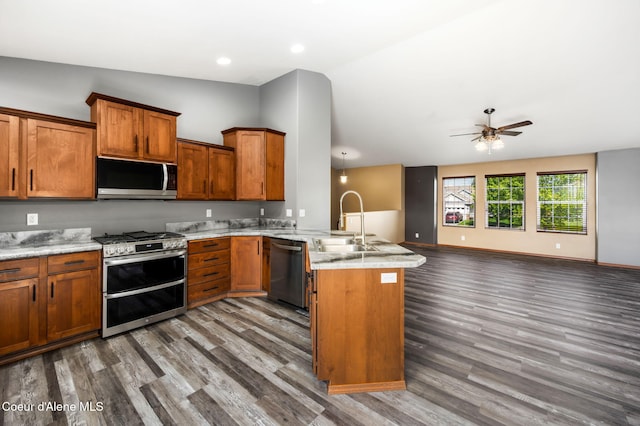 kitchen with a peninsula, lofted ceiling, open floor plan, a sink, and stainless steel appliances