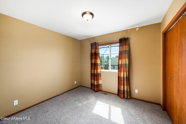 unfurnished bedroom with carpet flooring, baseboards, visible vents, and a closet