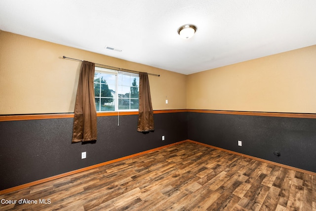 spare room featuring visible vents, baseboards, and wood finished floors