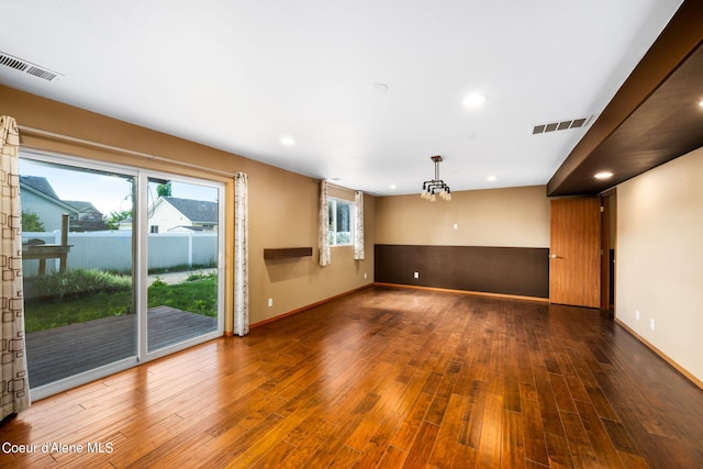 unfurnished living room with hardwood / wood-style flooring and a notable chandelier