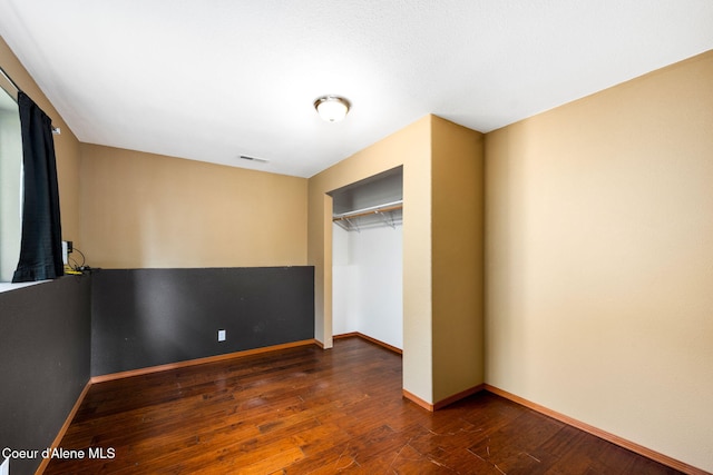 unfurnished bedroom featuring dark wood-type flooring and a closet