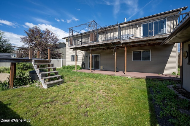 rear view of property featuring a yard, a patio, and a wooden deck