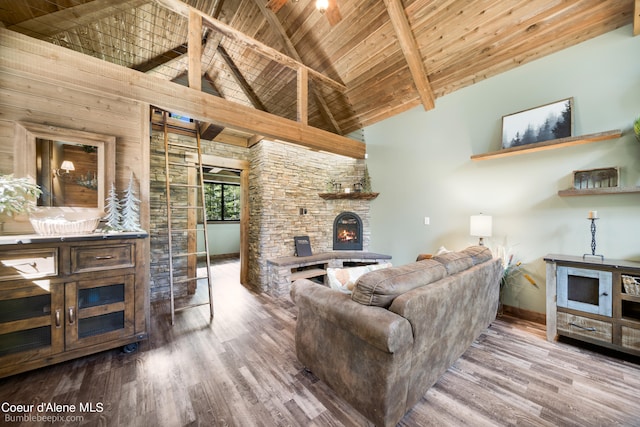 living room featuring a stone fireplace, hardwood / wood-style flooring, beam ceiling, and high vaulted ceiling