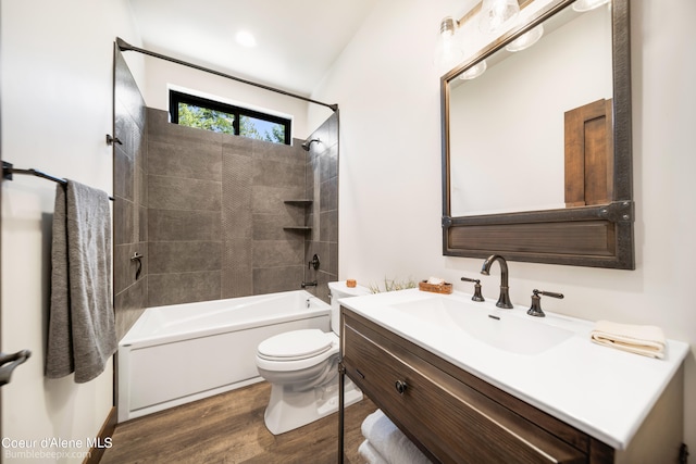 full bathroom with vanity, wood-type flooring, tiled shower / bath, vaulted ceiling, and toilet