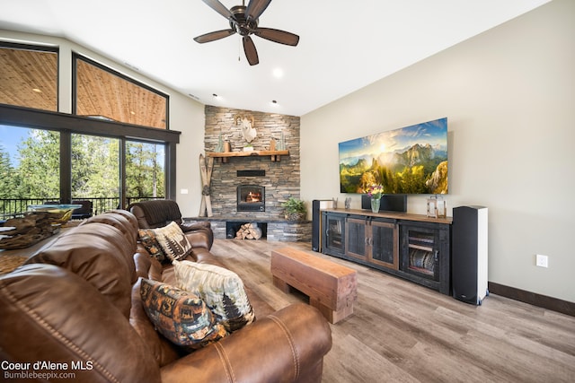 living room featuring lofted ceiling, ceiling fan, a stone fireplace, and hardwood / wood-style floors