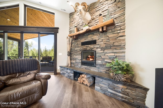 living room with a fireplace, hardwood / wood-style flooring, and a towering ceiling