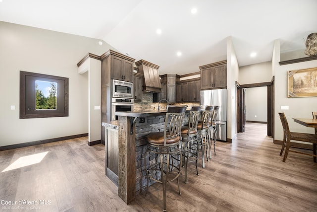 kitchen featuring appliances with stainless steel finishes, hardwood / wood-style flooring, a breakfast bar, and an island with sink