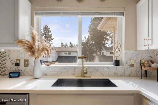 room details featuring sink, white cabinetry, and backsplash