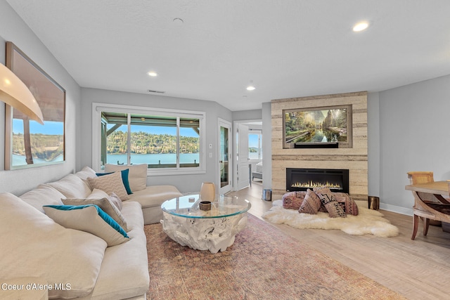 living room with a water view, a fireplace, and wood-type flooring