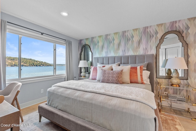 bedroom with a water view and hardwood / wood-style floors