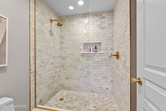 bathroom featuring a tile shower and toilet