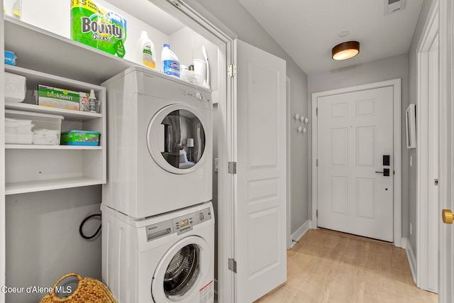 laundry room featuring light wood-type flooring and stacked washer / dryer