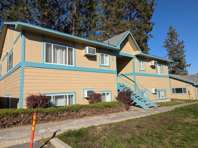 view of side of home featuring a wall mounted air conditioner and a yard