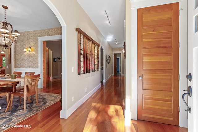 hallway with hardwood / wood-style flooring and a notable chandelier