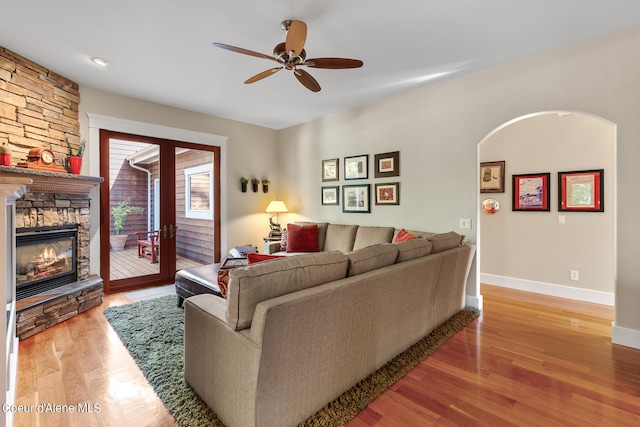 living room with ceiling fan, light wood-type flooring, and a fireplace