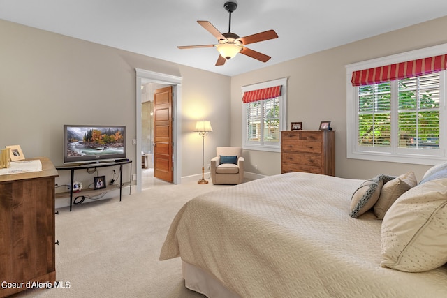 carpeted bedroom with ensuite bath and ceiling fan