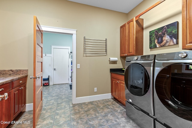 clothes washing area featuring cabinets, dark tile patterned floors, and washing machine and dryer