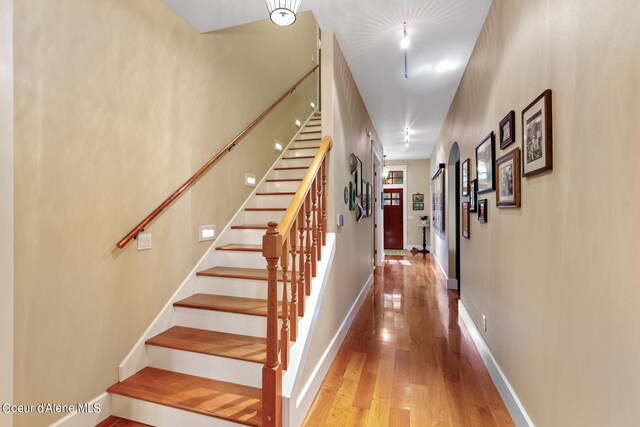 staircase featuring a towering ceiling and wood-type flooring