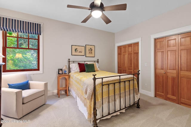 carpeted bedroom featuring multiple closets and ceiling fan