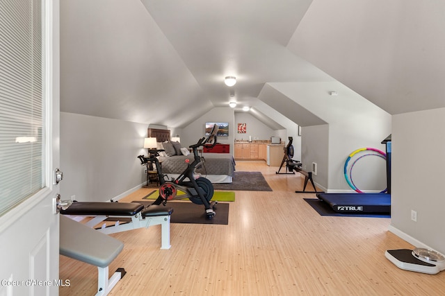 exercise area with vaulted ceiling and light hardwood / wood-style flooring