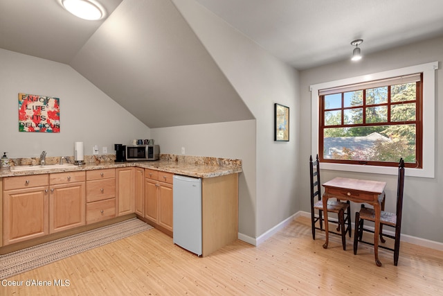 kitchen featuring white dishwasher, sink, light brown cabinetry, light wood-type flooring, and vaulted ceiling