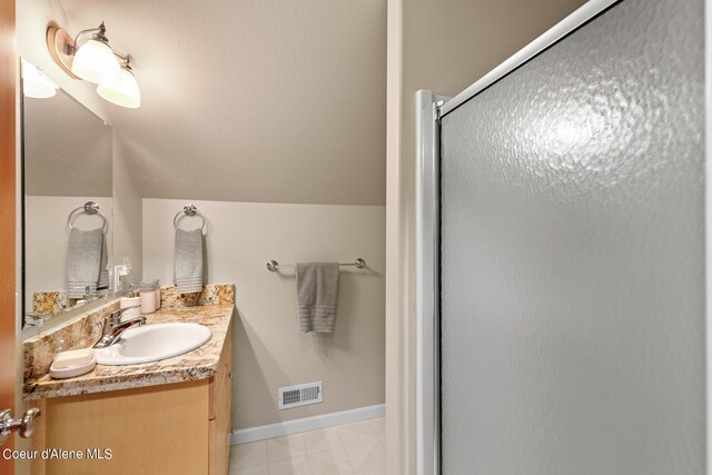 bathroom with vanity, vaulted ceiling, and a shower with door