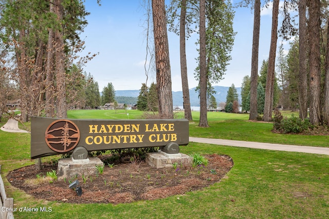 community sign with a mountain view and a lawn