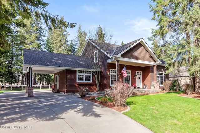 craftsman house featuring a carport, a front lawn, a shingled roof, and concrete driveway